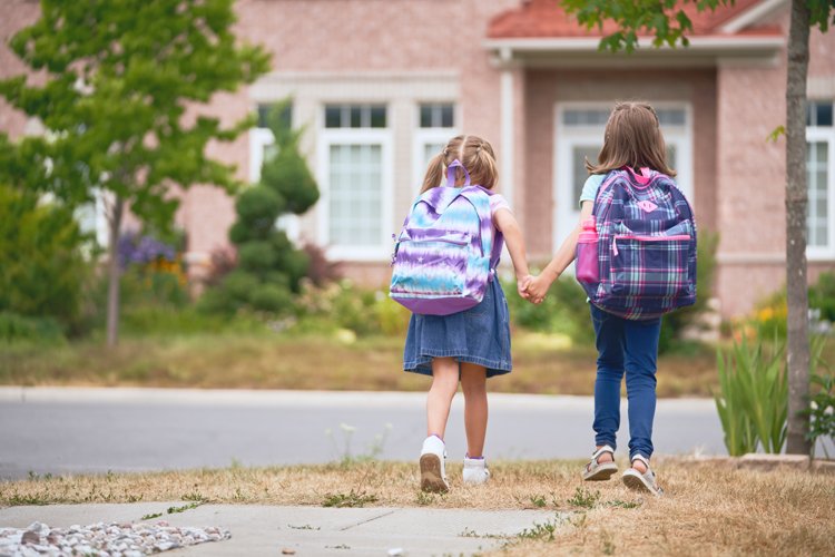 zwei Mädchen Hand in Hand auf dem Schulweg