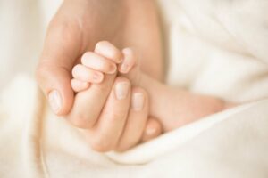 mutter haelt die hand ihres neugeborenen babys