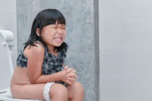 kleines Mädchen sitzt mit Schmerzen auf Toilette