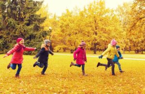 Kinder rennen im Herbst auf einer Wiese herum
