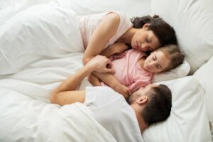Eltern liegen mit Kind zusammen im Bett