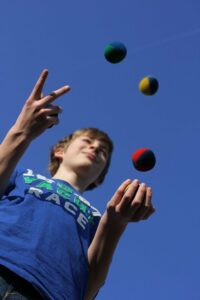 ein kind trainiert seine koordinativen faehigkeiten beim jonglieren