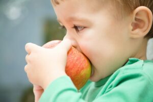 kleiner Junge isst einen Apfel