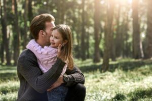 Vater umarmt seine Tochter im Wald