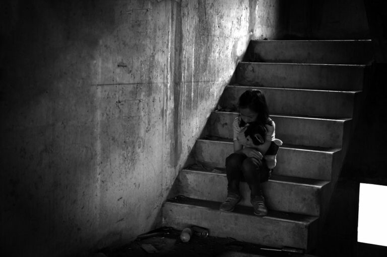 Kind sitzt traurig auf treppe
