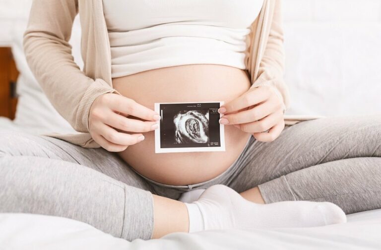 frau hält ultraschallbild vor babybauch